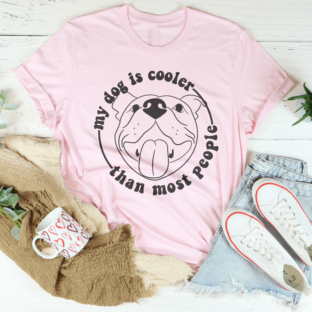 A stylish t-shirt featuring the phrase 'My Dog Is Cooler Than Most People' printed on it, made from soft cotton fabric.