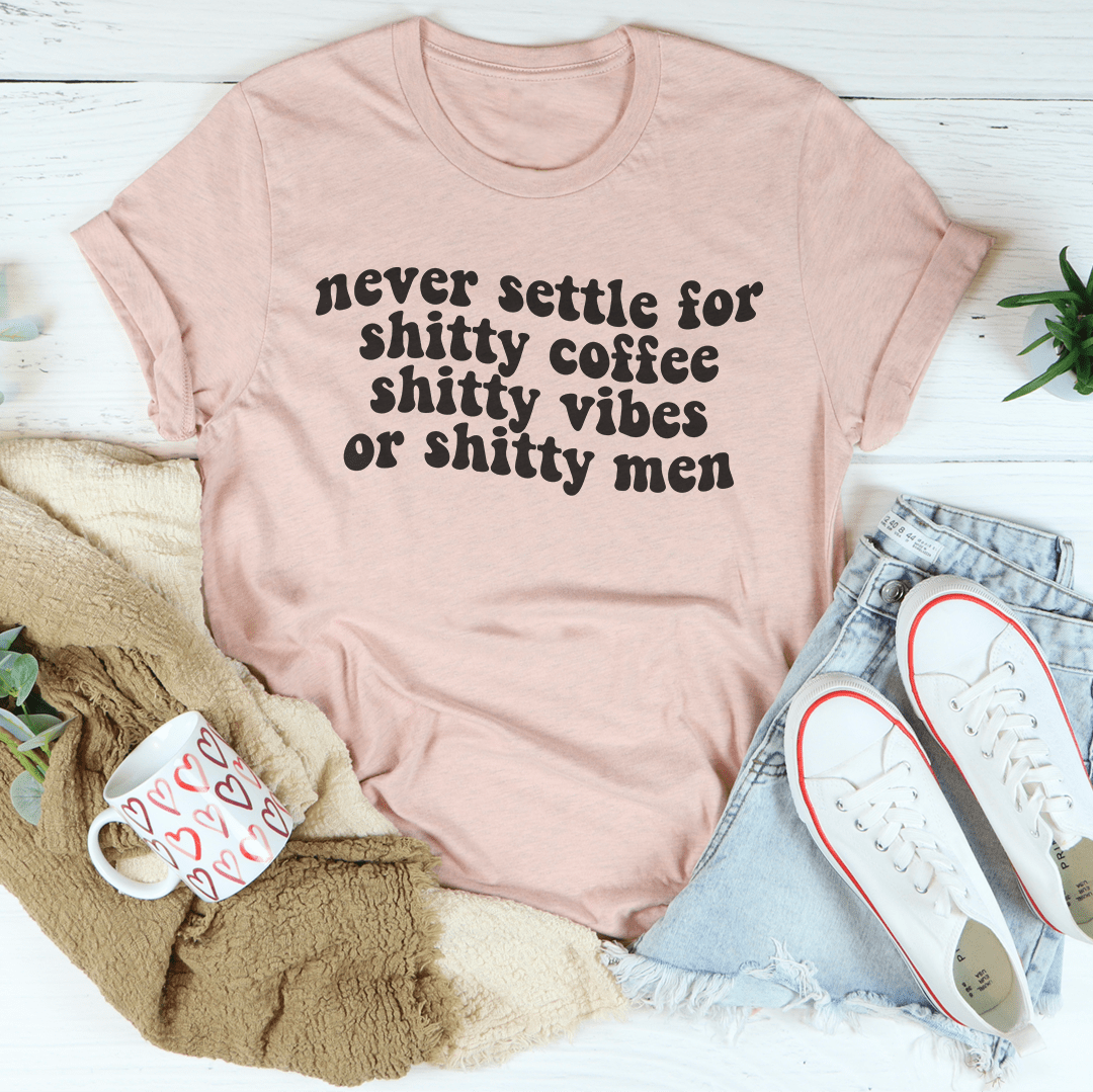 A stylish black t-shirt with the phrase 'Never Settle For Shitty Coffee' printed in bold white letters, showcasing its comfortable fabric and durable stitching.