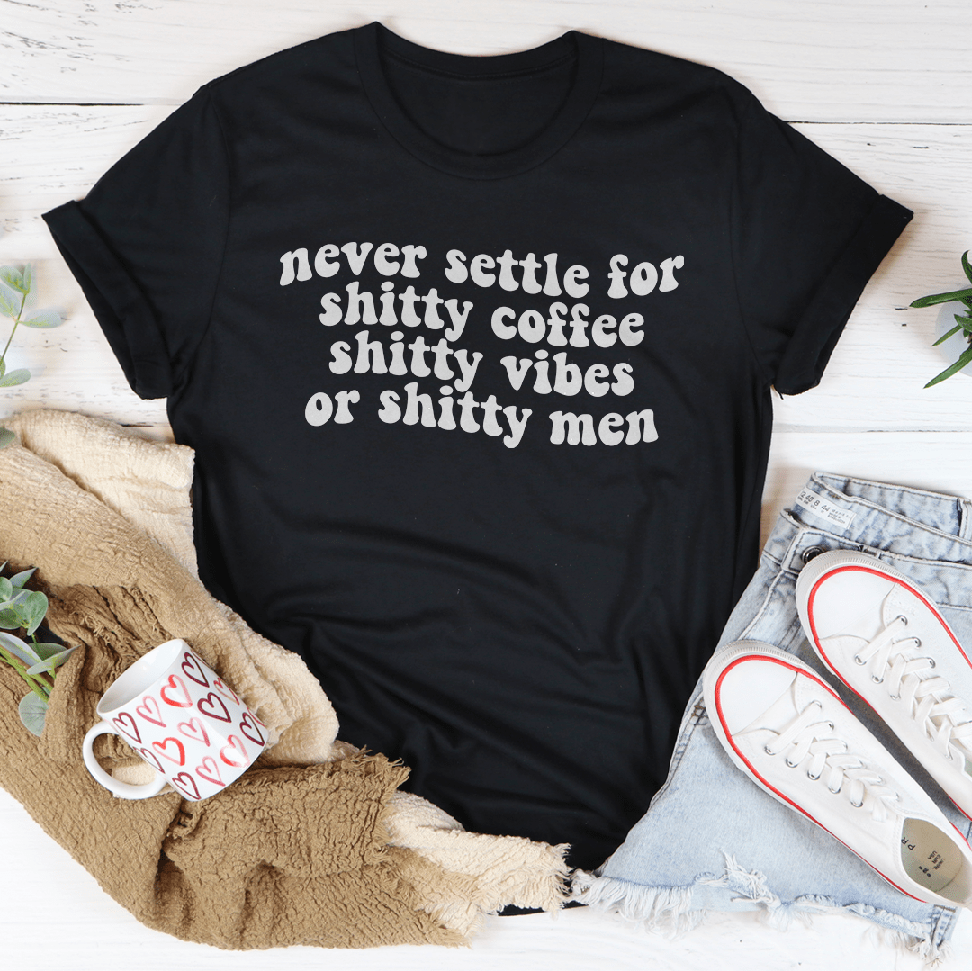 A stylish black t-shirt with the phrase 'Never Settle For Shitty Coffee' printed in bold white letters, showcasing its comfortable fabric and durable stitching.