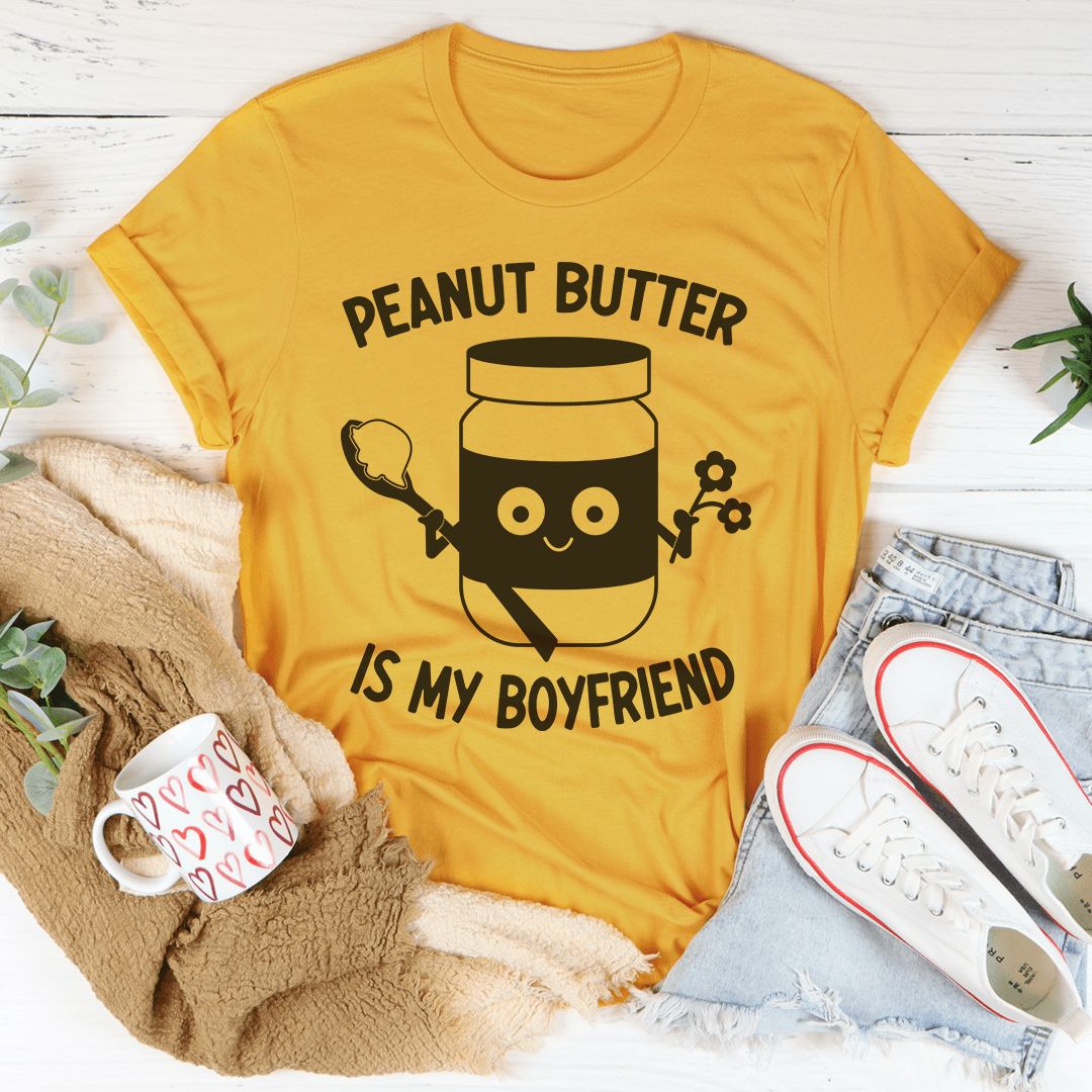 A soft, comfortable t-shirt featuring the phrase 'Peanut Butter Is My Boyfriend' in a playful font, perfect for casual wear.