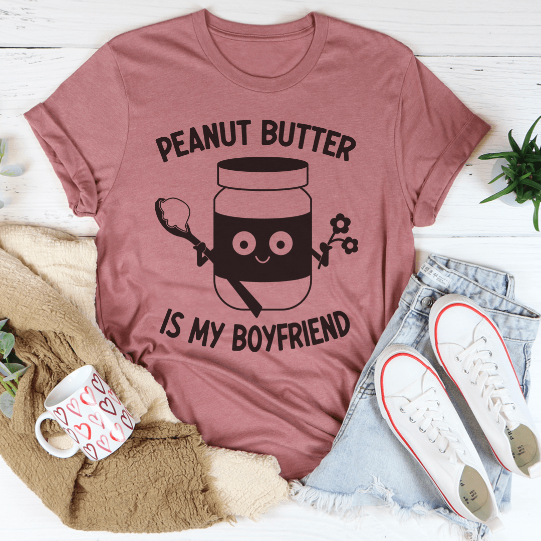 A soft, comfortable t-shirt featuring the phrase 'Peanut Butter Is My Boyfriend' in a playful font, perfect for casual wear.