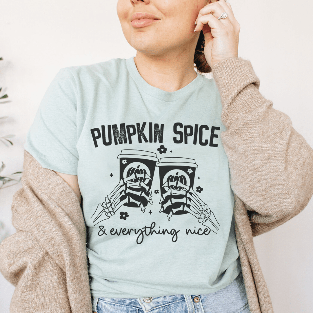 Pumpkin Spice & Everything Nice T-Shirt displayed on a wooden background, showcasing its soft fabric and vibrant autumn-themed design.