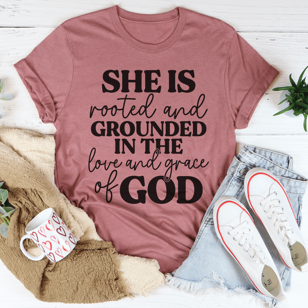 A comfortable and stylish t-shirt featuring the phrase 'She Is Rooted And Grounded In The Love And Grace Of God' printed on it, showcasing its soft fabric and durable stitching.