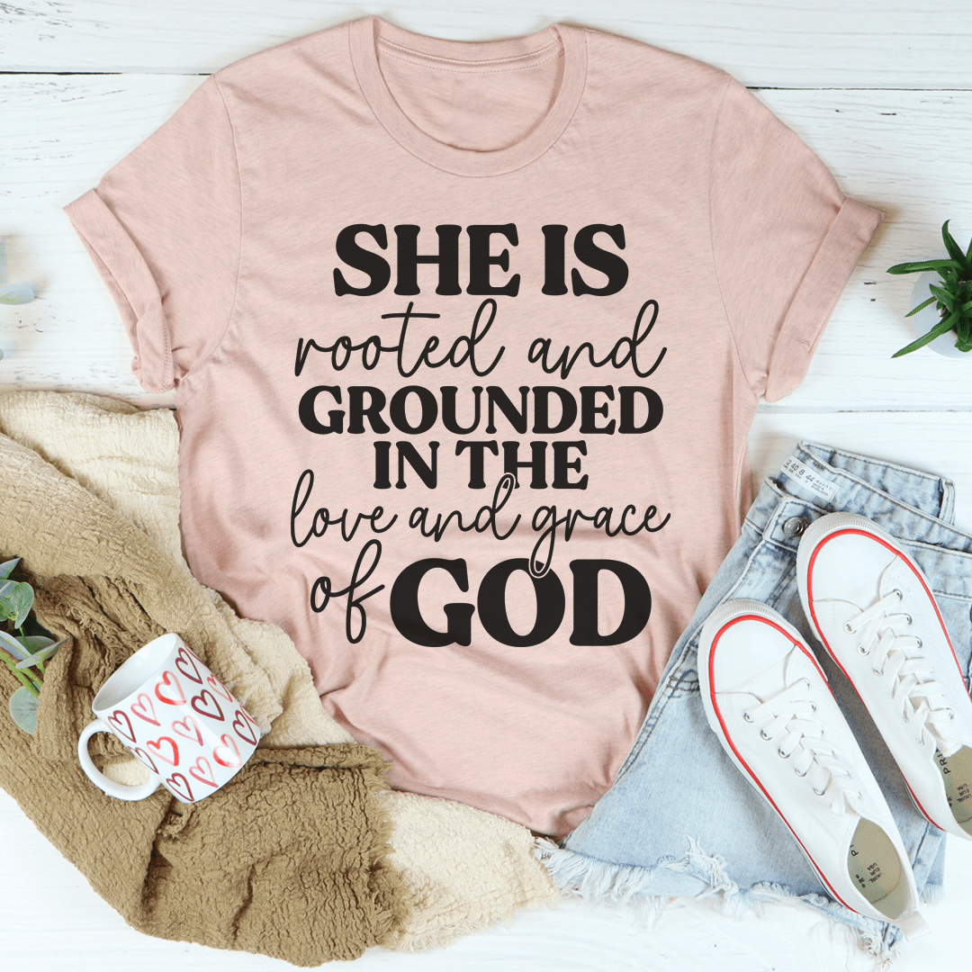 A comfortable and stylish t-shirt featuring the phrase 'She Is Rooted And Grounded In The Love And Grace Of God' printed on it, showcasing its soft fabric and durable stitching.