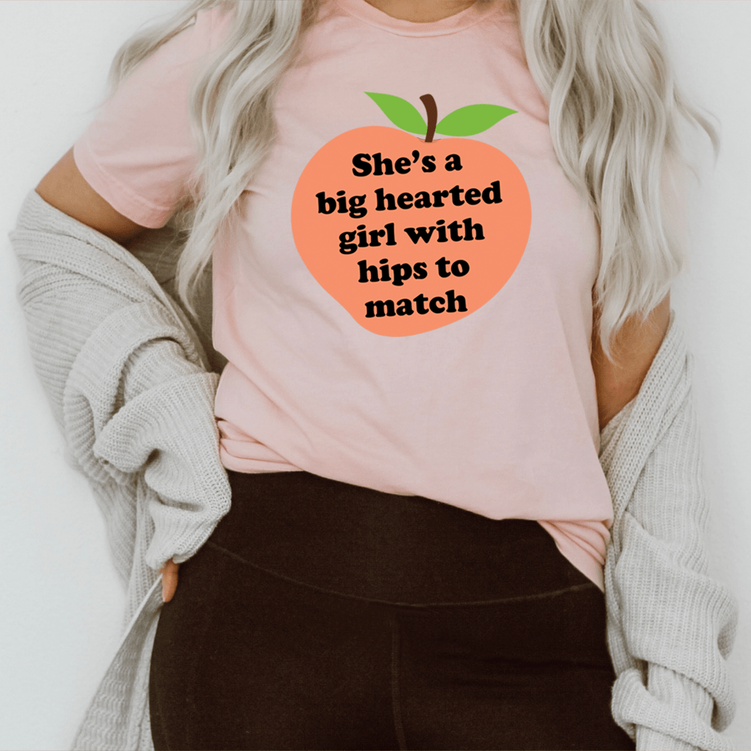 A stylish t-shirt featuring the phrase 'She's A Big Hearted Girl With Hips to Match', made from soft cotton with durable stitching.