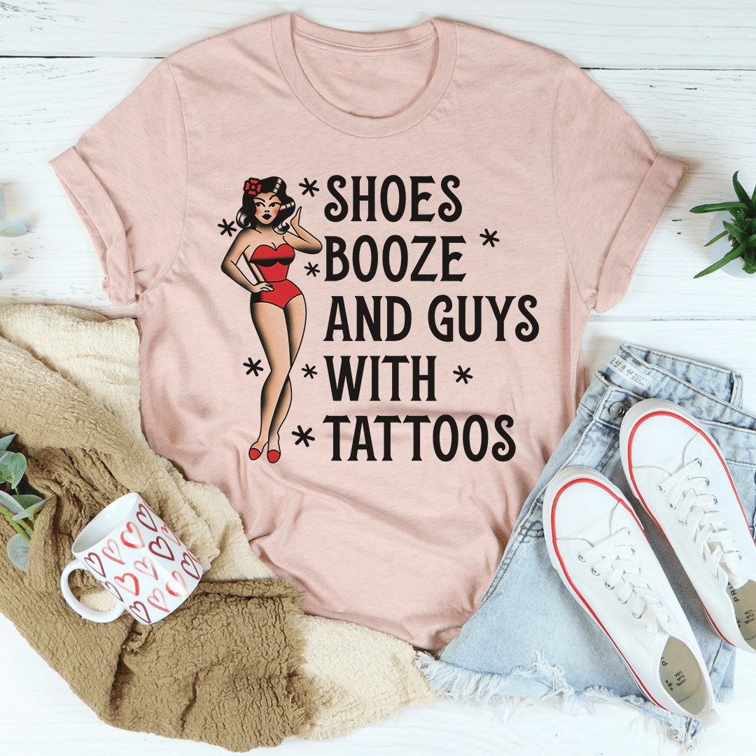 A stylish black t-shirt featuring the phrase 'Shoes Booze And Guys With Tattoos' printed in bold letters, showcasing its comfortable fabric and double stitching.