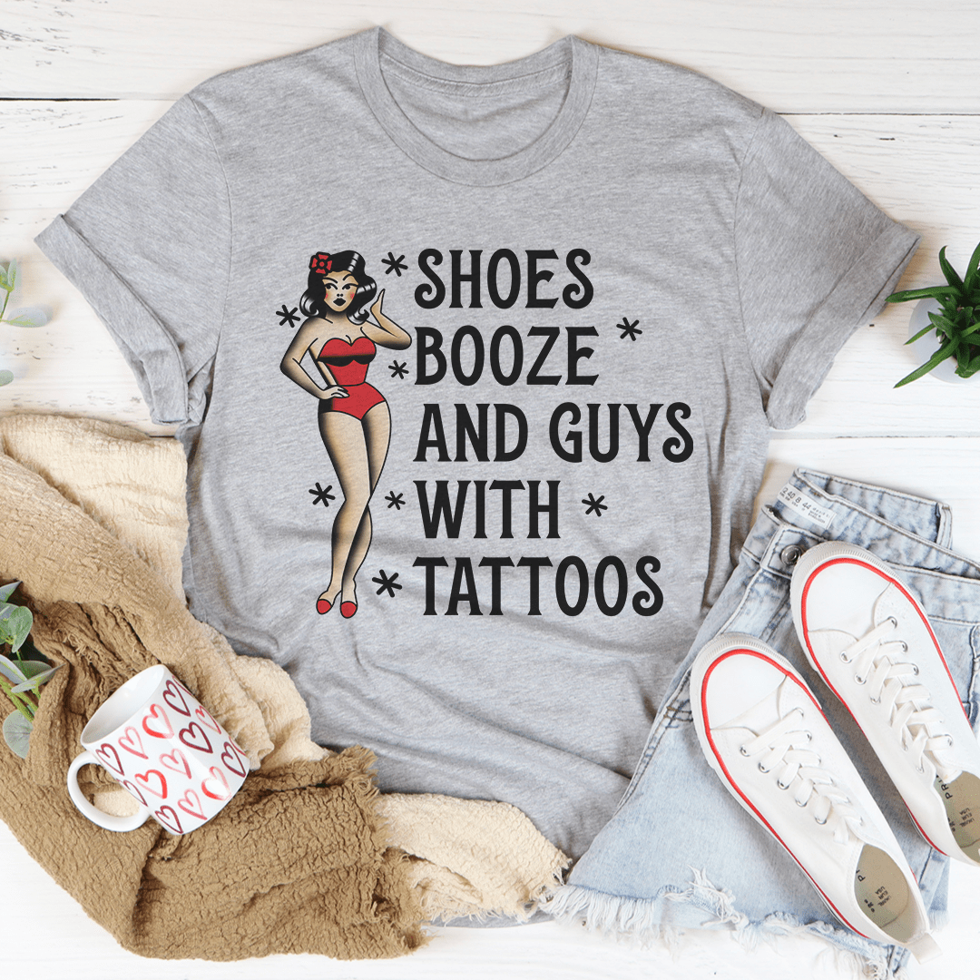 A stylish black t-shirt featuring the phrase 'Shoes Booze And Guys With Tattoos' printed in bold letters, showcasing its comfortable fabric and double stitching.