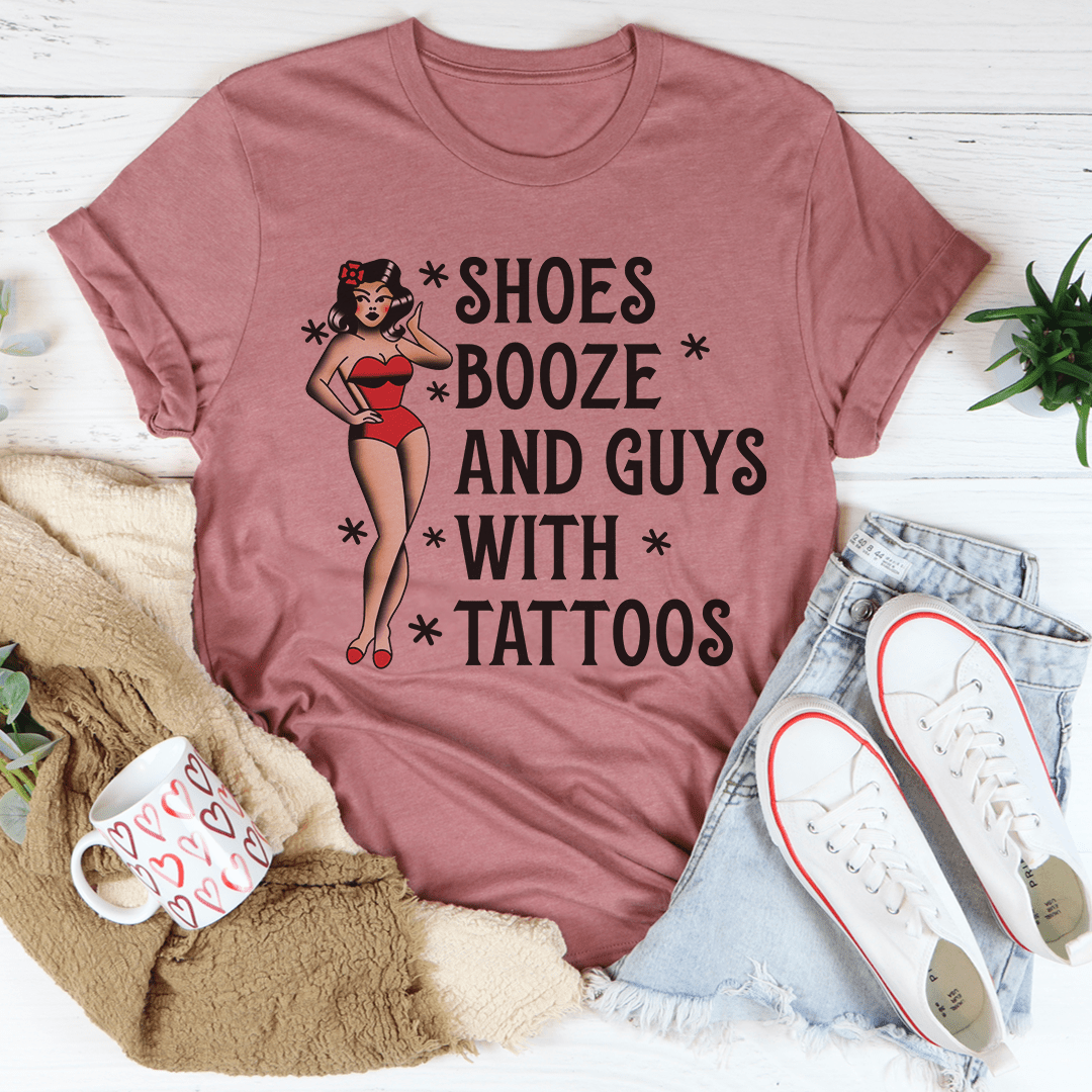 A stylish black t-shirt featuring the phrase 'Shoes Booze And Guys With Tattoos' printed in bold letters, showcasing its comfortable fabric and double stitching.