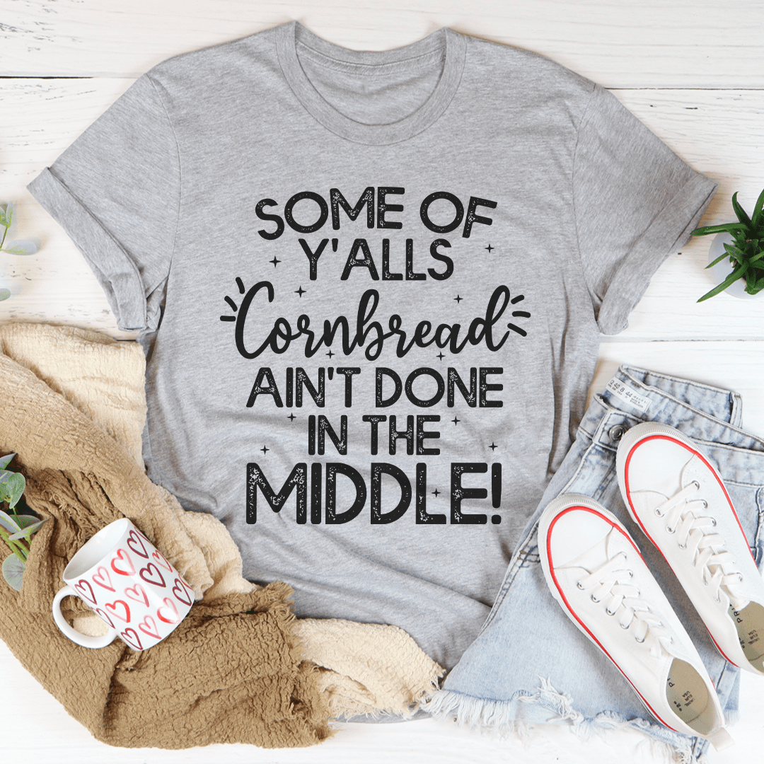 A comfortable and stylish t-shirt featuring the phrase 'Some Of Y'Alls Cornbread Ain't Done In The Middle' printed on it, showcasing its soft fabric and durable stitching.