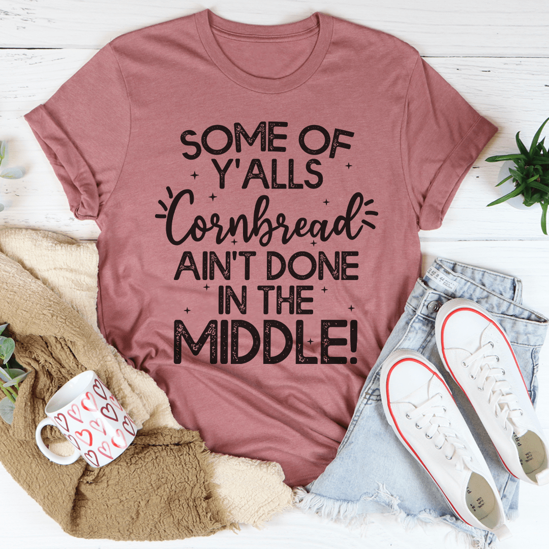 A comfortable and stylish t-shirt featuring the phrase 'Some Of Y'Alls Cornbread Ain't Done In The Middle' printed on it, showcasing its soft fabric and durable stitching.