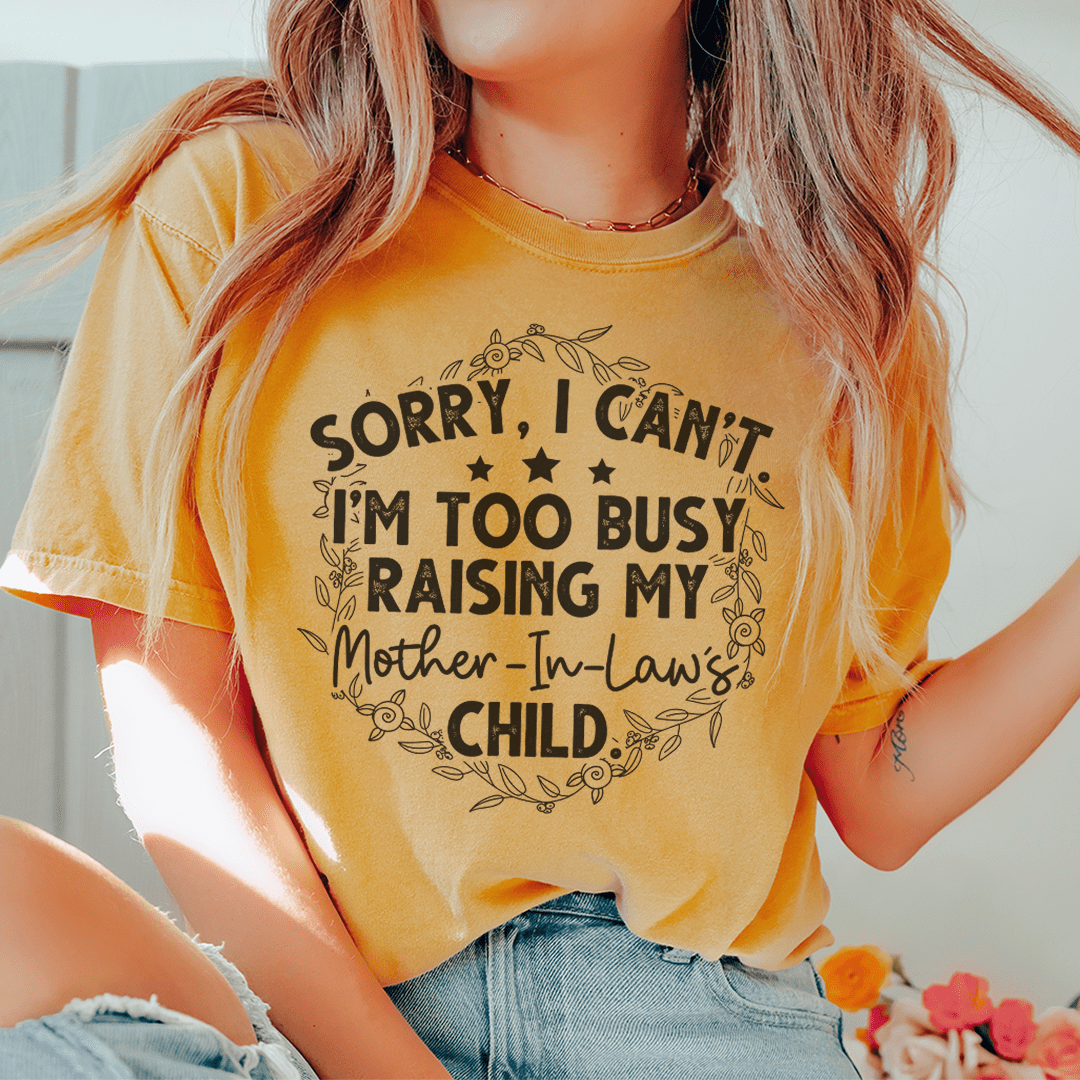 A humorous t-shirt featuring the phrase 'Sorry I Can't I'm Too Busy Raising My Mother In Law's Child', made of soft cotton.