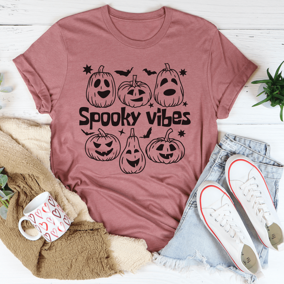 A cozy Spooky Vibes Pumpkins Tee featuring a vibrant pumpkin graphic, perfect for Halloween celebrations.