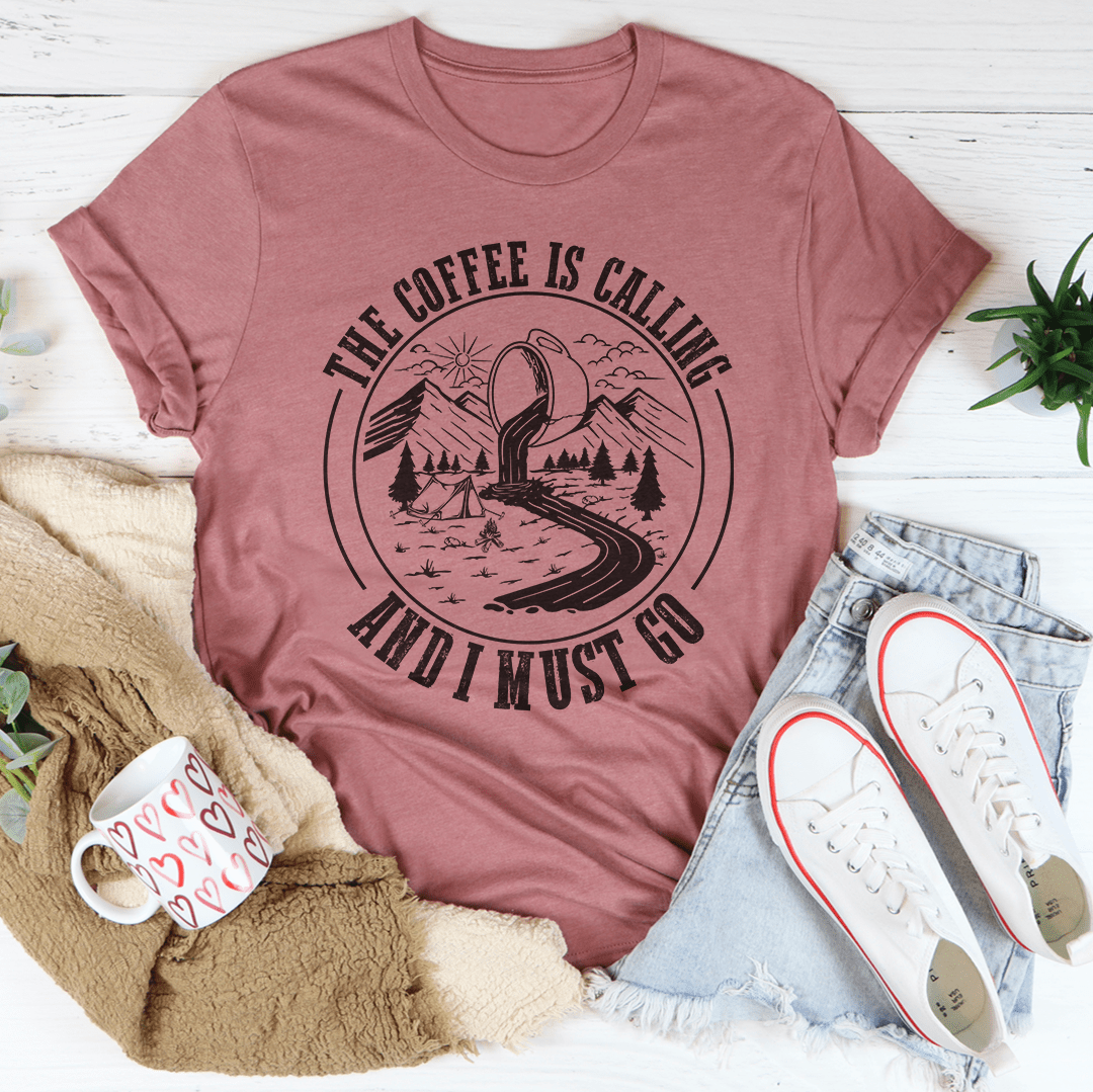 A stylish t-shirt featuring the phrase 'The Coffee Is Calling And I Must Go', made from soft ring-spun cotton with double stitching for durability.