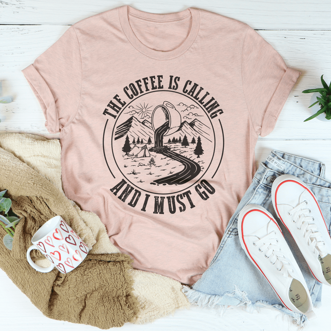 A stylish t-shirt featuring the phrase 'The Coffee Is Calling And I Must Go', made from soft ring-spun cotton with double stitching for durability.