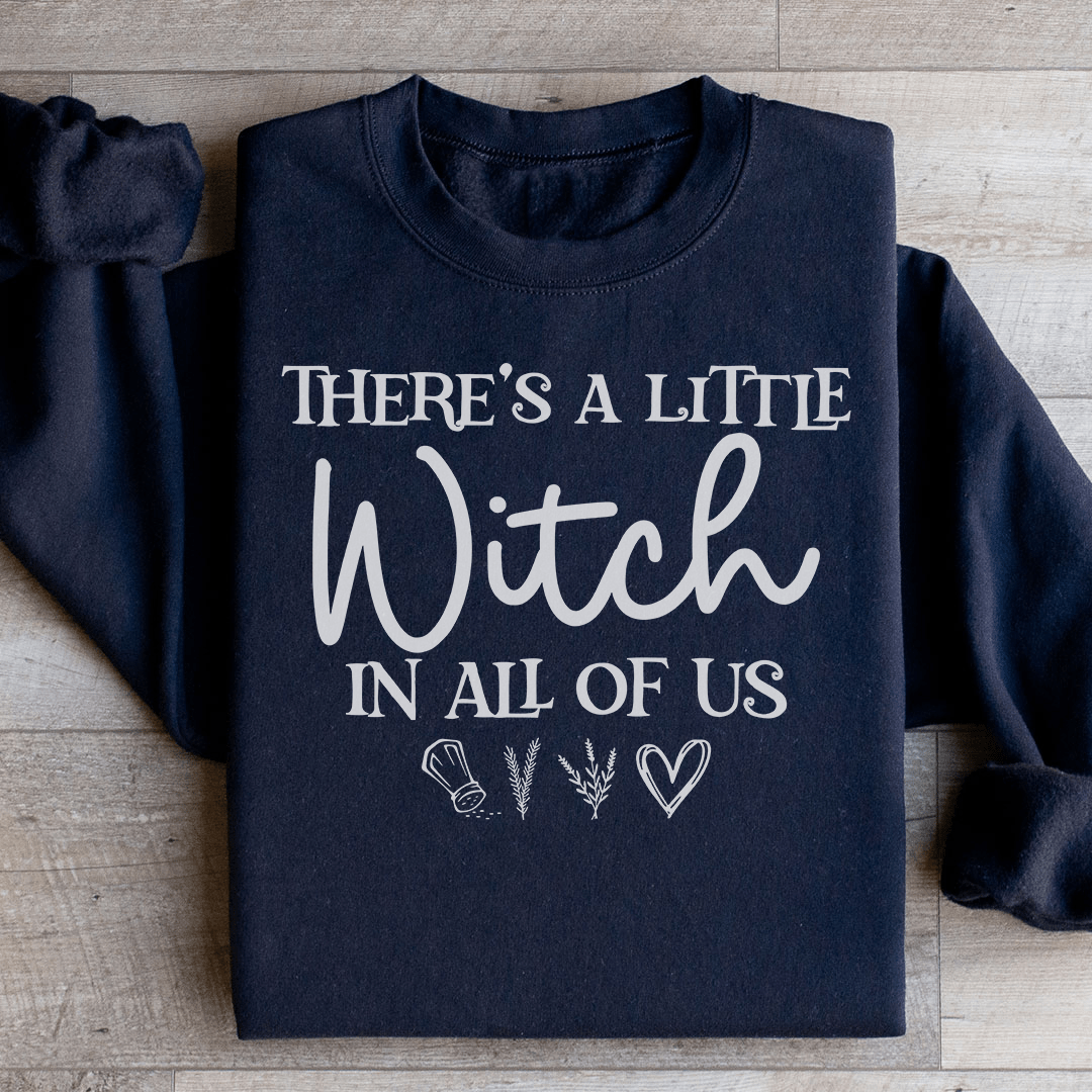 A stylish black t-shirt featuring the phrase 'There's A Little Witch In All Of Us' in a whimsical font, showcasing its soft fabric and durable stitching.