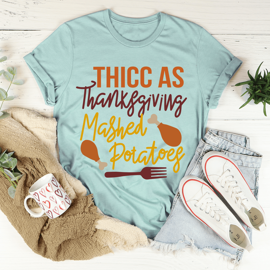 Thicc As Thanksgiving Mashed Potatoes T-Shirt displayed on a hanger, showcasing its soft cotton fabric and double stitching.