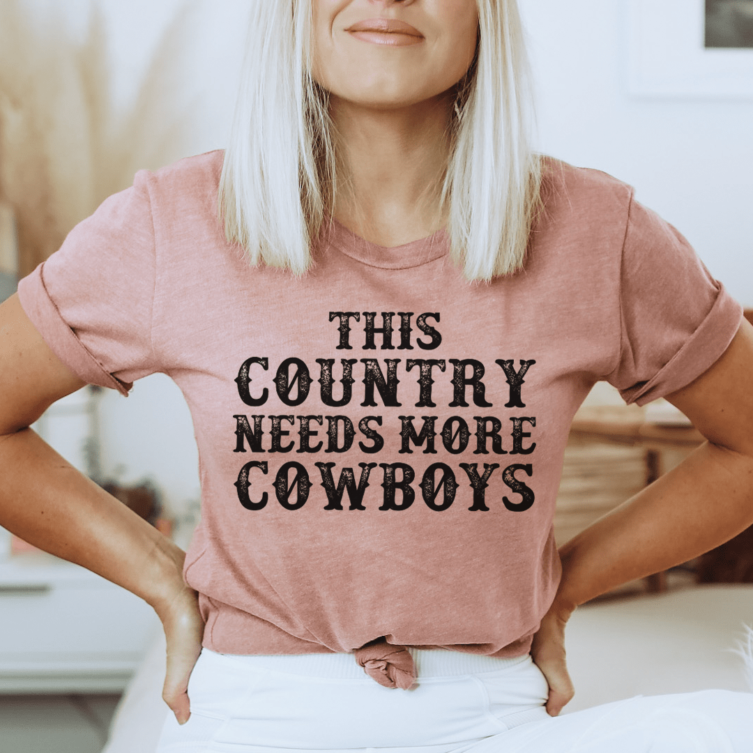 This Country Needs More Cowboys Tee featuring a bold cowboy-themed print on a soft, durable cotton fabric.