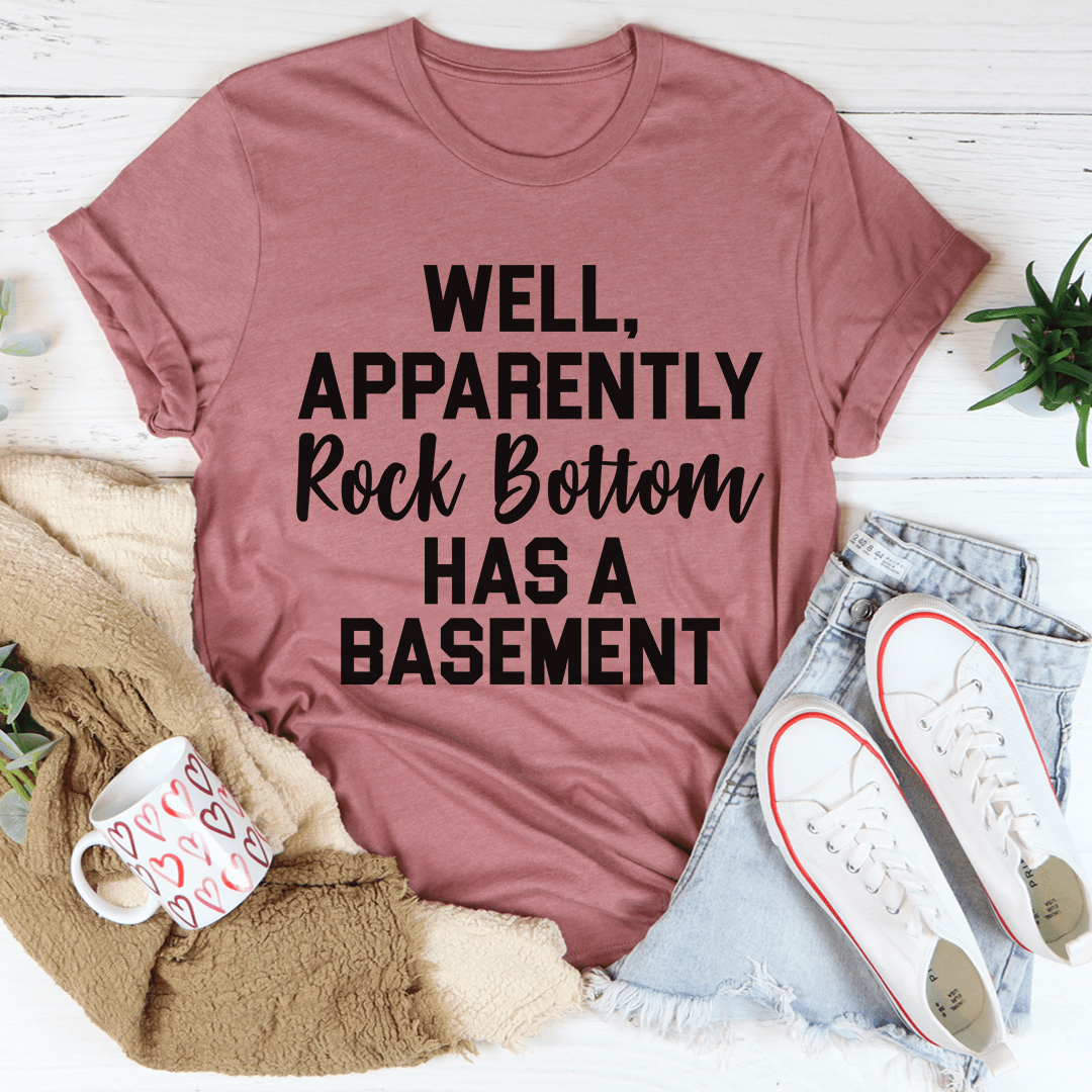 A stylish t-shirt featuring the phrase 'Well Apparently Rock Bottom Has A Basement', made from soft ring-spun cotton with double stitching.