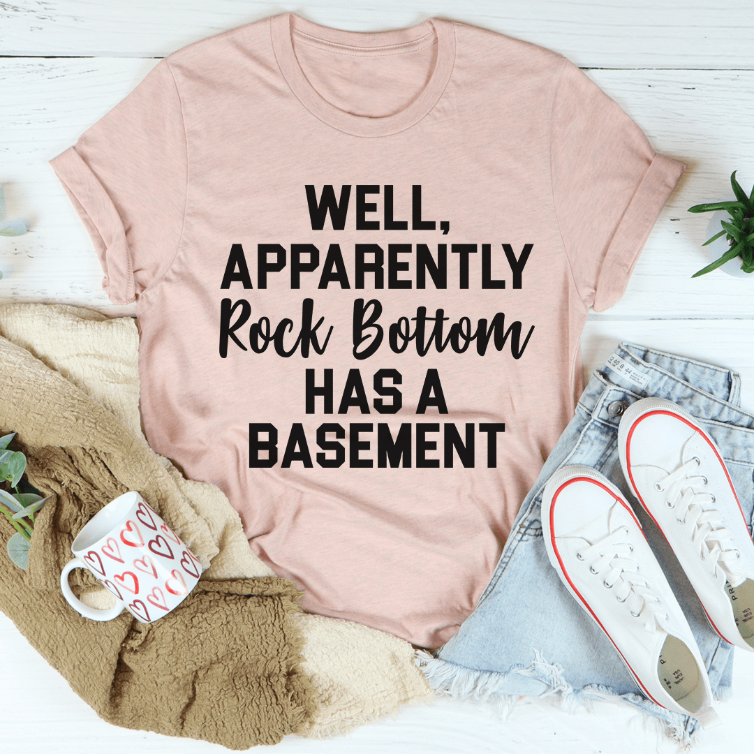 A stylish t-shirt featuring the phrase 'Well Apparently Rock Bottom Has A Basement', made from soft ring-spun cotton with double stitching.