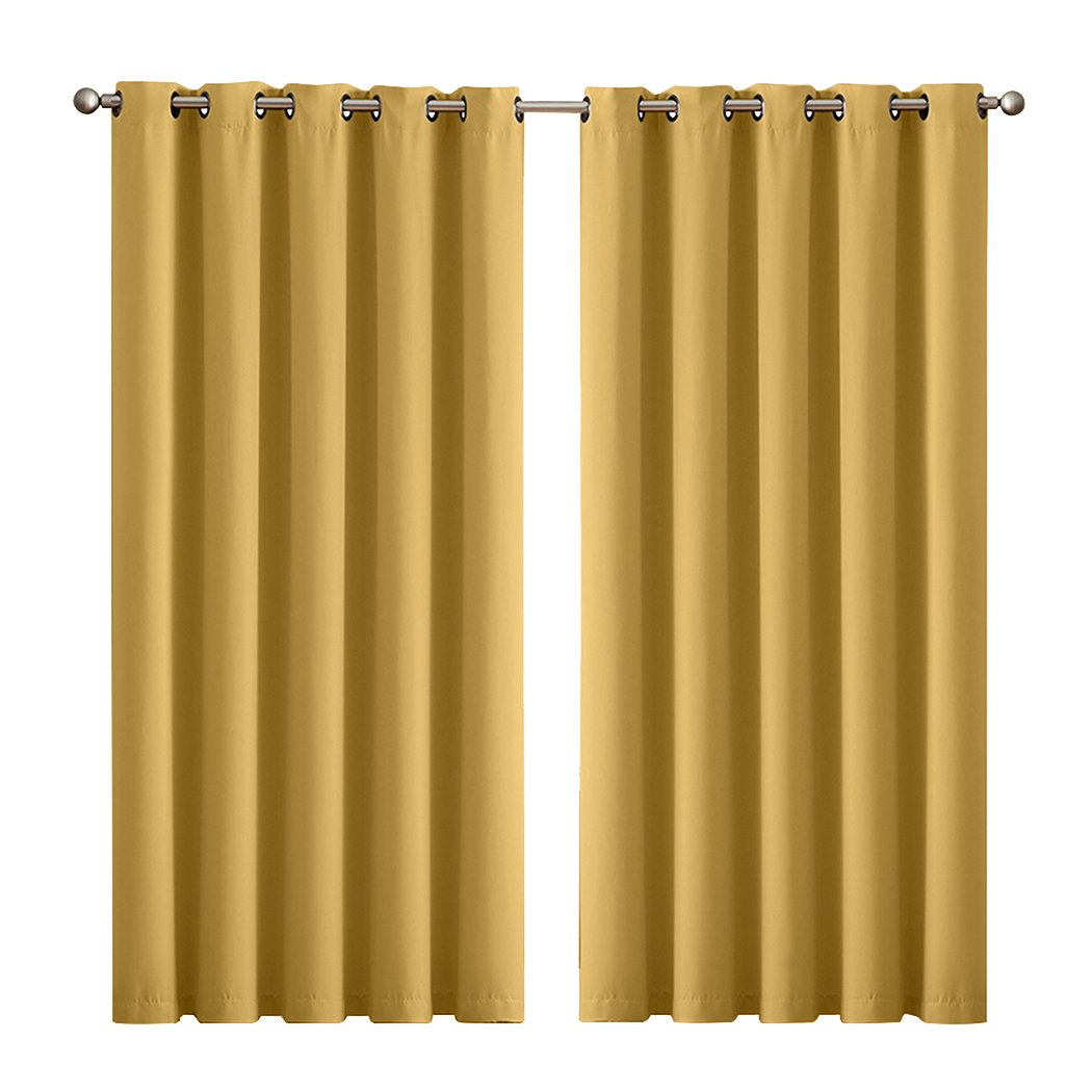 Two elegant blockout curtain panels in vibrant color, featuring eyelet design and triple weave fabric, hanging in a stylish room.