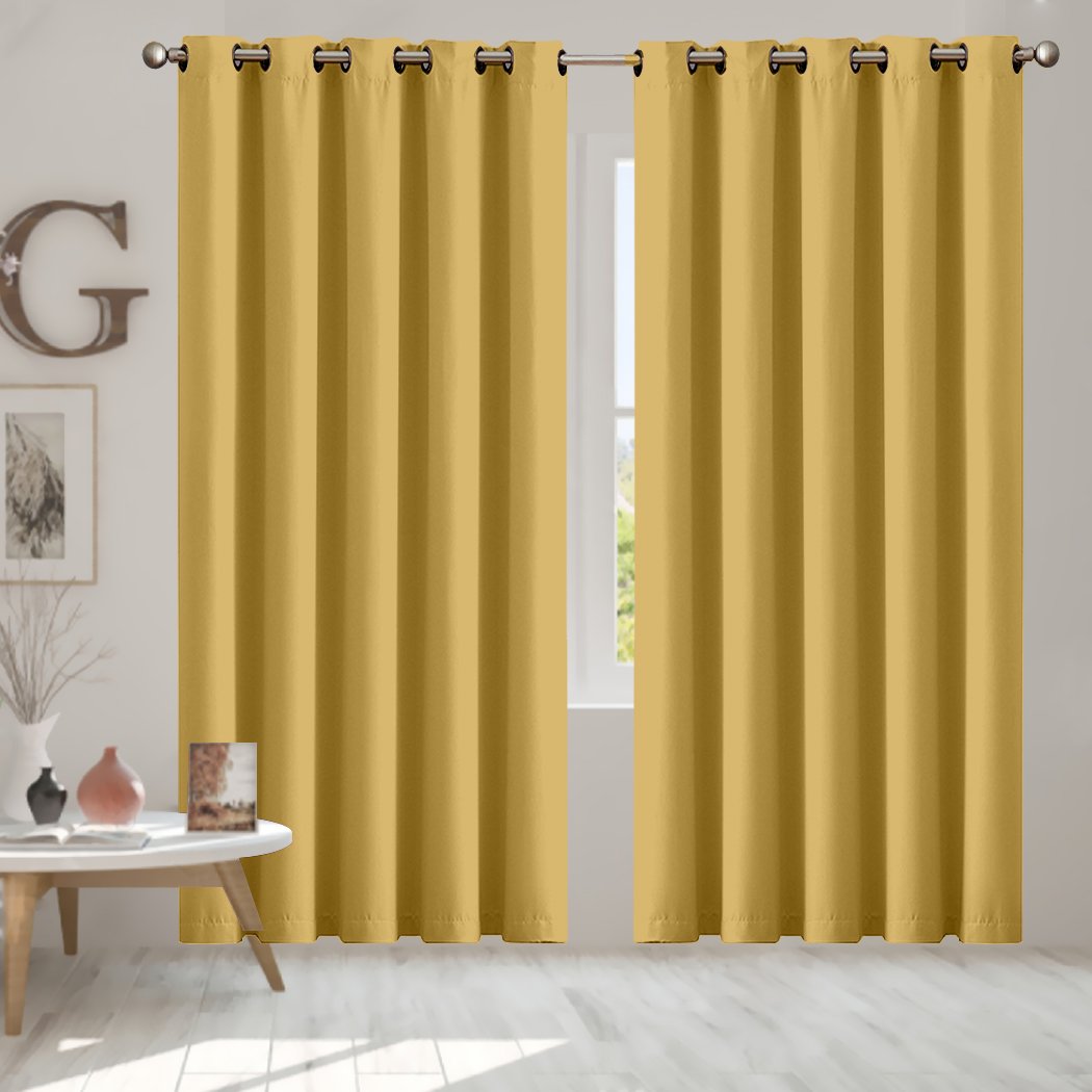 Two elegant blockout curtain panels in vibrant color, featuring eyelet design and triple weave fabric, hanging in a stylish room.