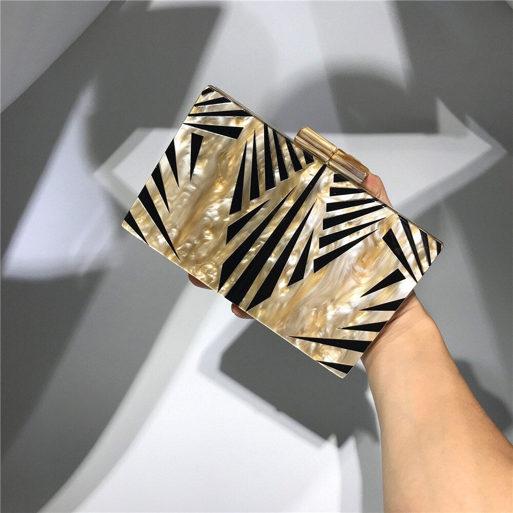 Acrylic luxury evening bag with a golden metal chain shoulder strap, featuring a stylish striped pattern and flap design.