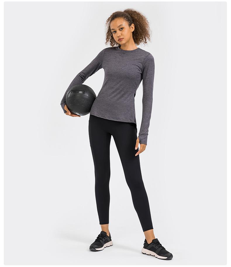 A stylish back open long sleeve training fitness yoga shirt for women, featuring a crew neck and thumb holes, perfect for workouts.