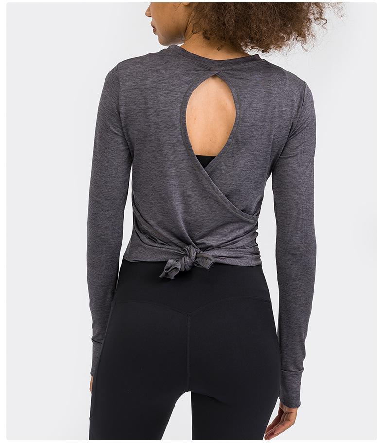 A stylish back open long sleeve training fitness yoga shirt for women, featuring a crew neck and thumb holes, perfect for workouts.