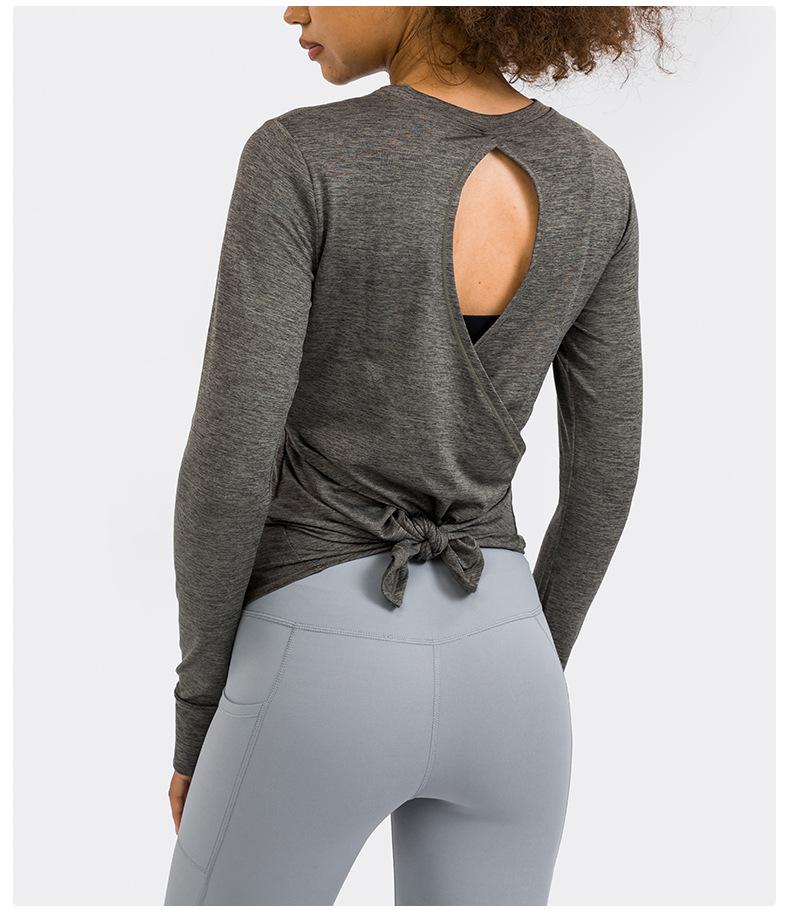 A stylish back open long sleeve training fitness yoga shirt for women, featuring a crew neck and thumb holes, perfect for workouts.