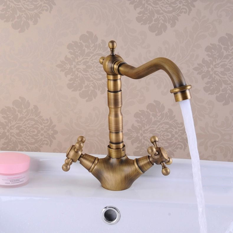 Antique brass bathroom sink faucet with 360-degree swivel spout and dual cross handles, showcasing elegant design and functionality.