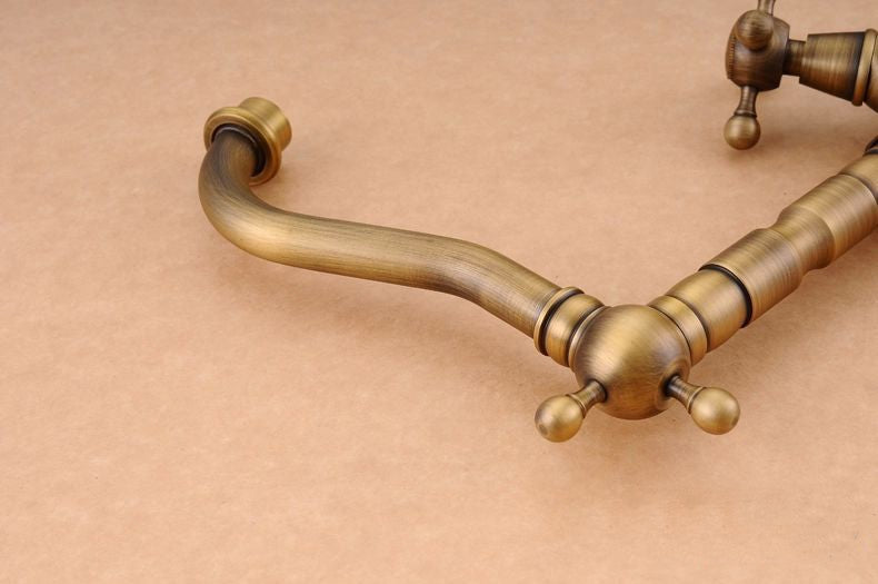 Antique brass bathroom sink faucet with 360-degree swivel spout and dual cross handles, showcasing elegant design and functionality.