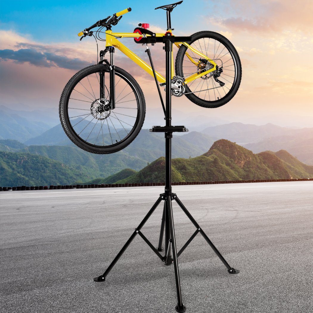 Ergonomic bike repair stand with tool tray, featuring a 360° swivel clamp and a sturdy four-legged base, ideal for home mechanics.