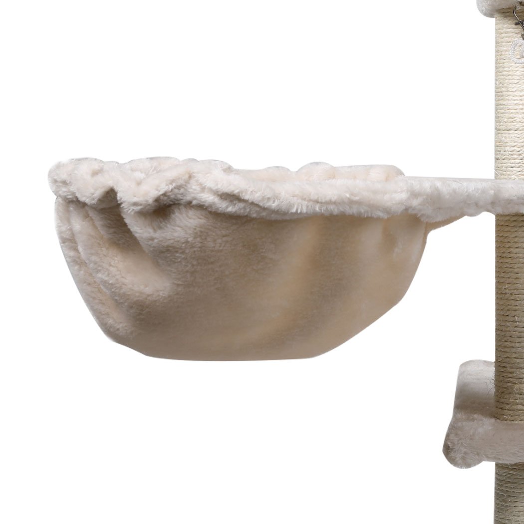 A beige multi-level cat tree tower with plush covering, sisal scratching posts, and hanging toys, designed for playful cats.