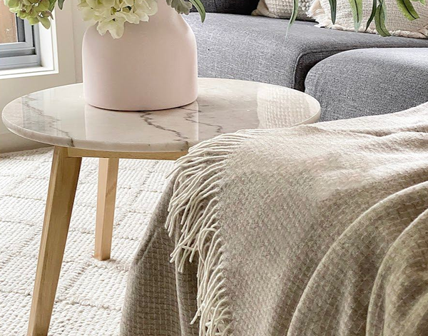 Chiswick Throw Blanket in beige, made from luxurious merino wool and cashmere, elegantly draped on a cozy sofa.