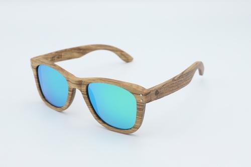 Classic sunglasses with zebra wood frames and polarized green lenses, displayed in a stylish wood box with microfiber accessories.