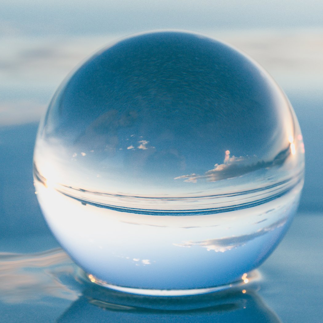 A clear glass healing crystal ball sphere, perfect for photography and home decor, displayed on a wooden surface with soft lighting.