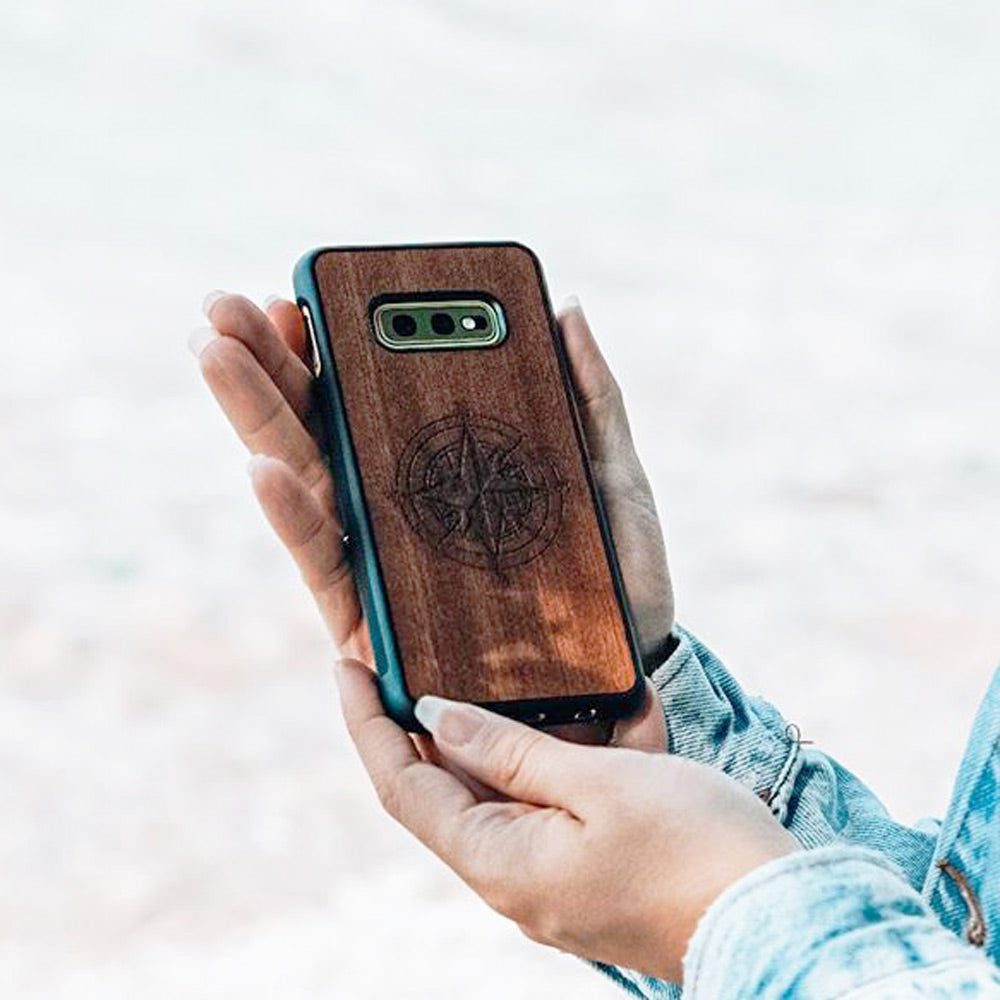 A beautifully crafted Mahogany wooden phone case, showcasing its unique grain and finish, held in a hand against a natural backdrop.