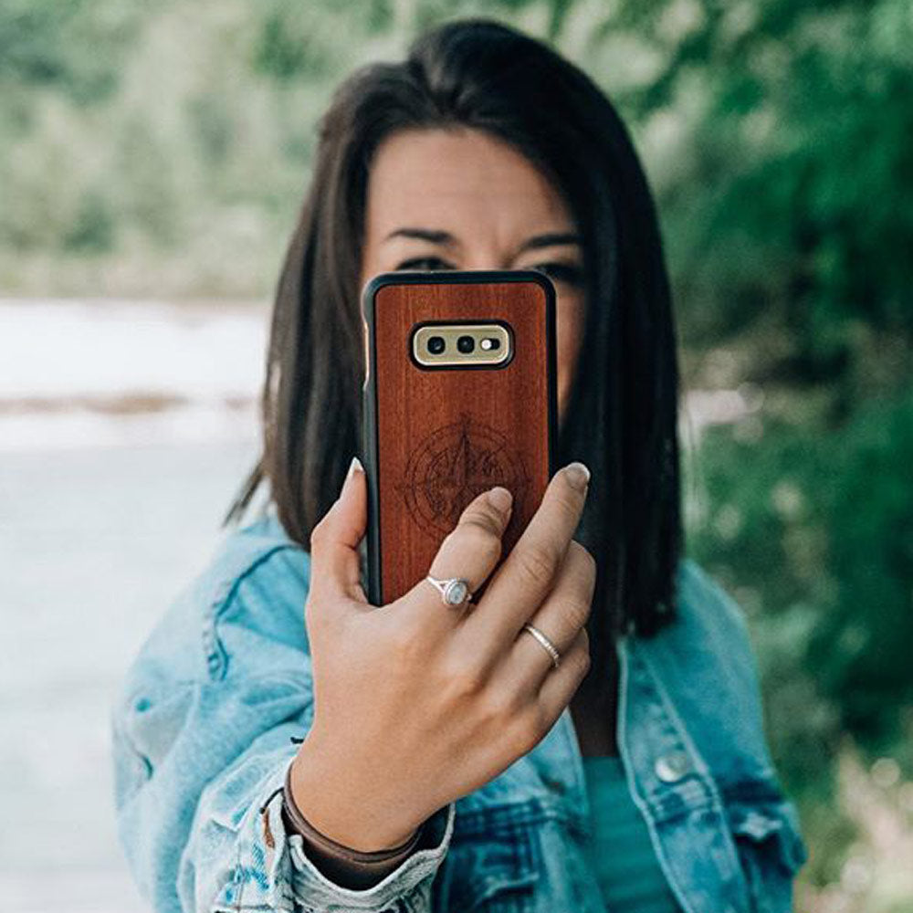 A beautifully crafted Mahogany wooden phone case, showcasing its unique grain and finish, held in a hand against a natural backdrop.