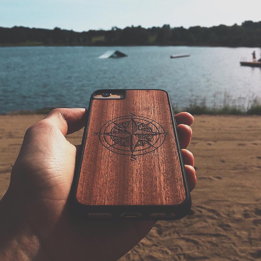 A beautifully crafted Mahogany wooden phone case, showcasing its unique grain and finish, held in a hand against a natural backdrop.