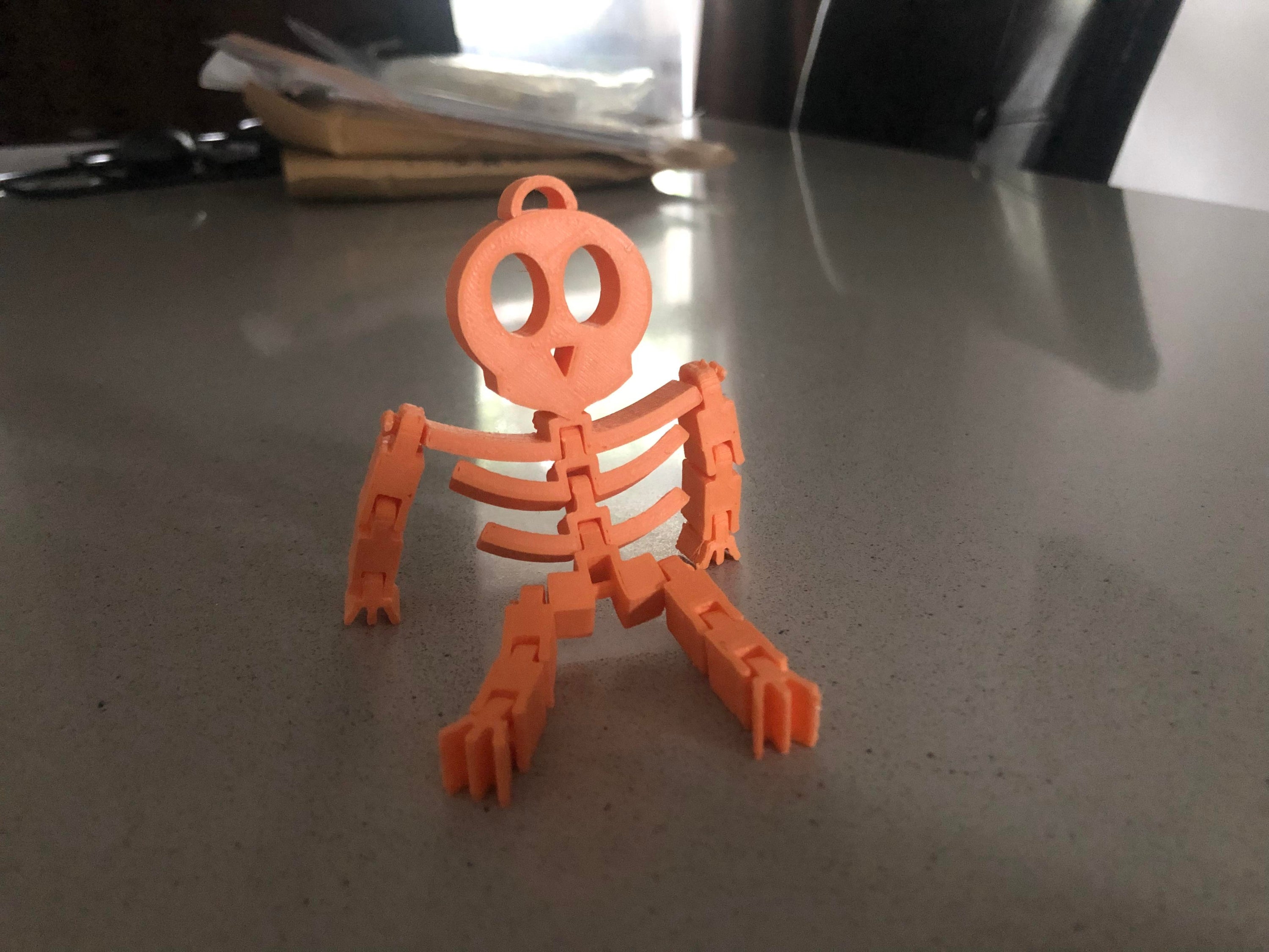 A flexible skeleton toy, 3.5 inches tall, posed playfully on a desk, perfect for Halloween decorations and office fun.