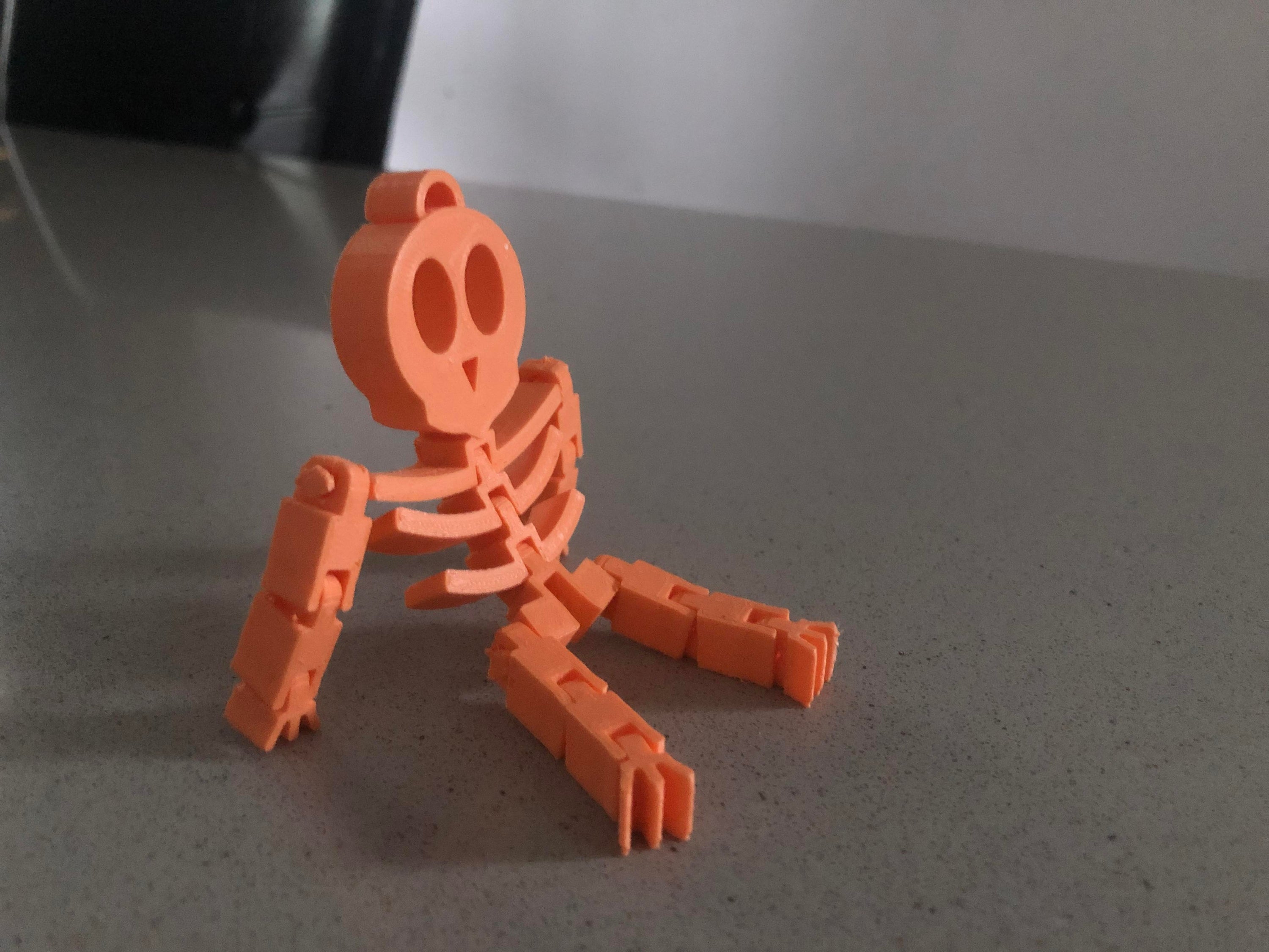 A flexible skeleton toy, 3.5 inches tall, posed playfully on a desk, perfect for Halloween decorations and office fun.