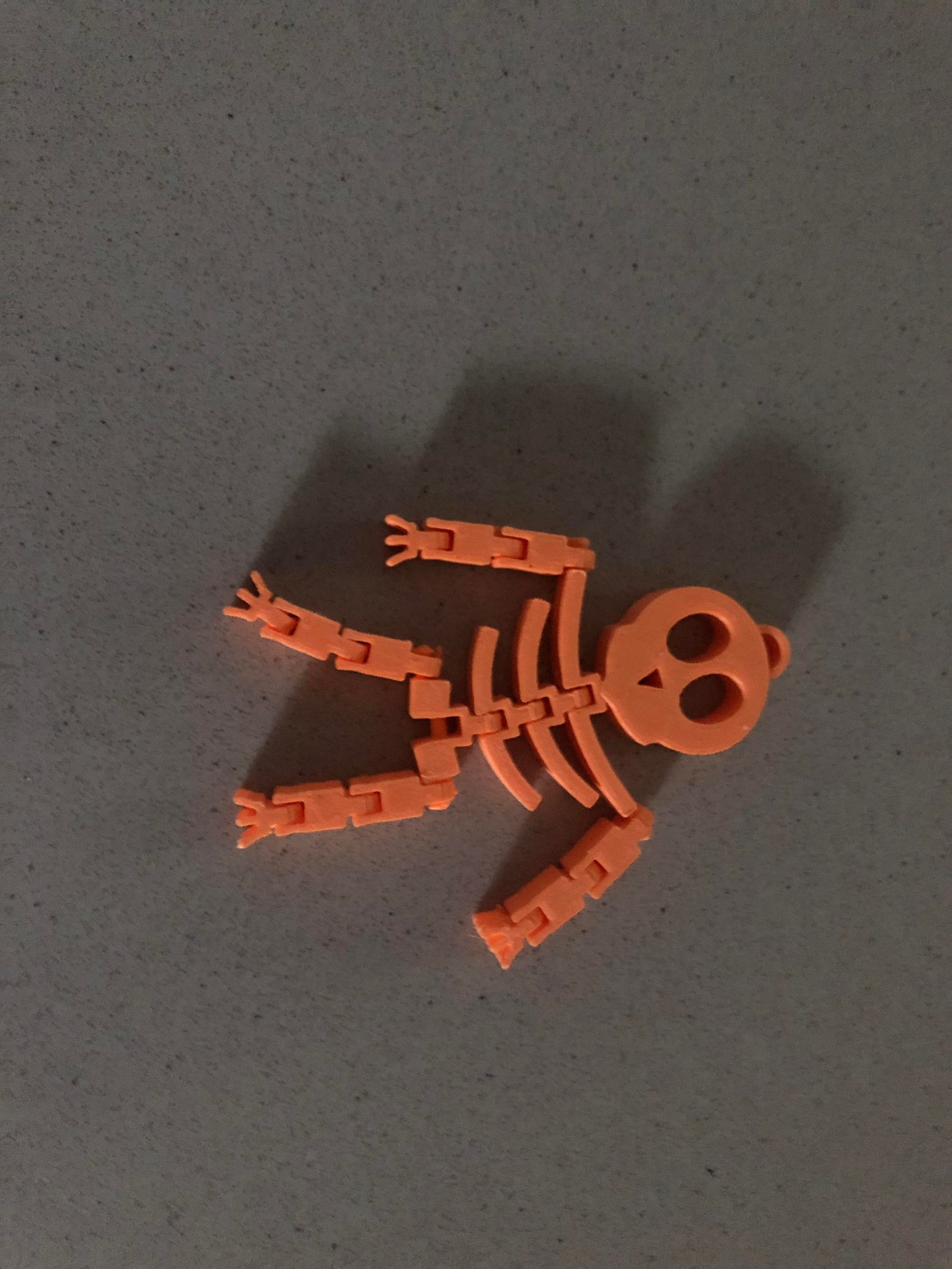 A flexible skeleton toy, 3.5 inches tall, posed playfully on a desk, perfect for Halloween decorations and office fun.