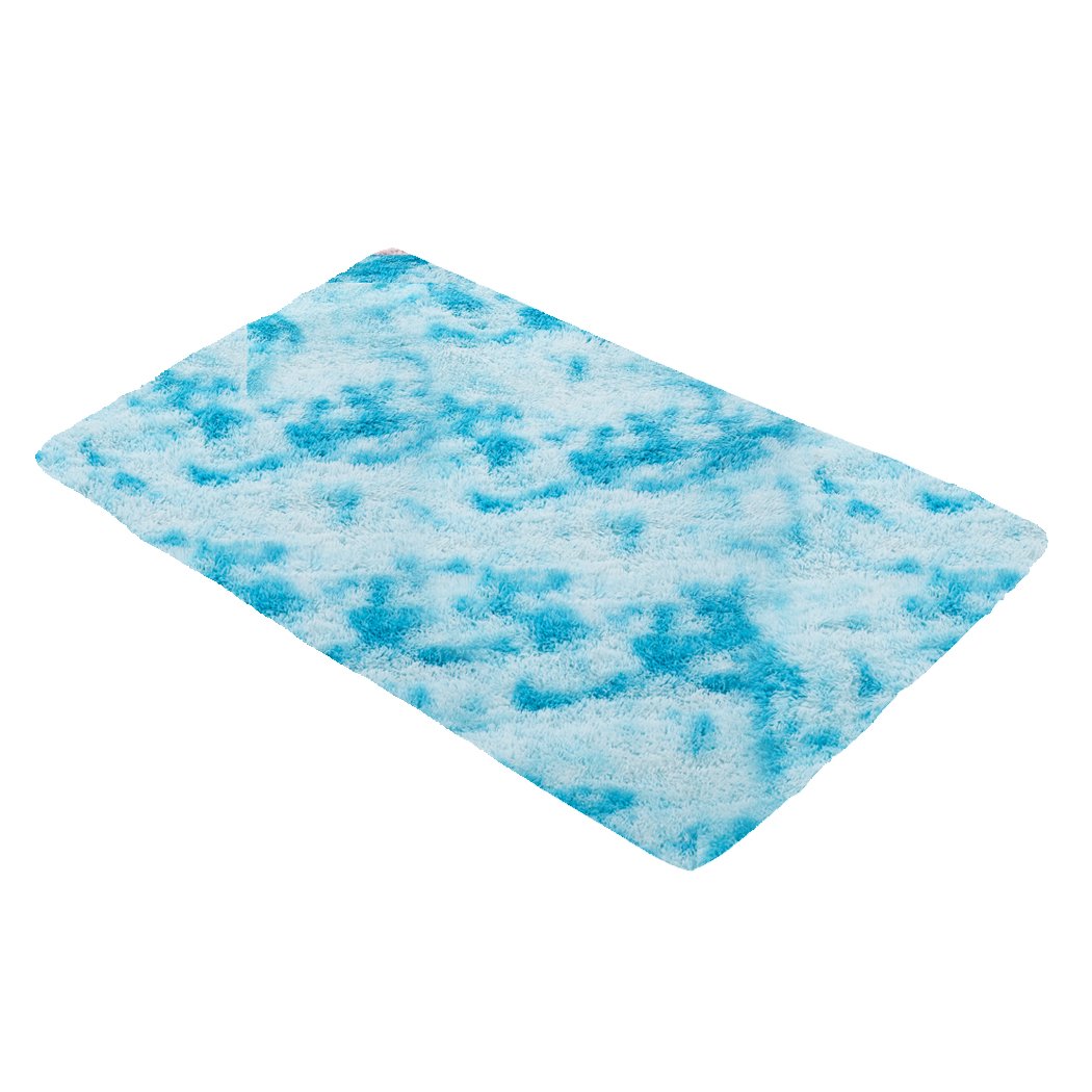 A large, soft shaggy floor rug with a vibrant tie-dyed pattern, showcasing its plush texture and anti-slip silicone bottom.