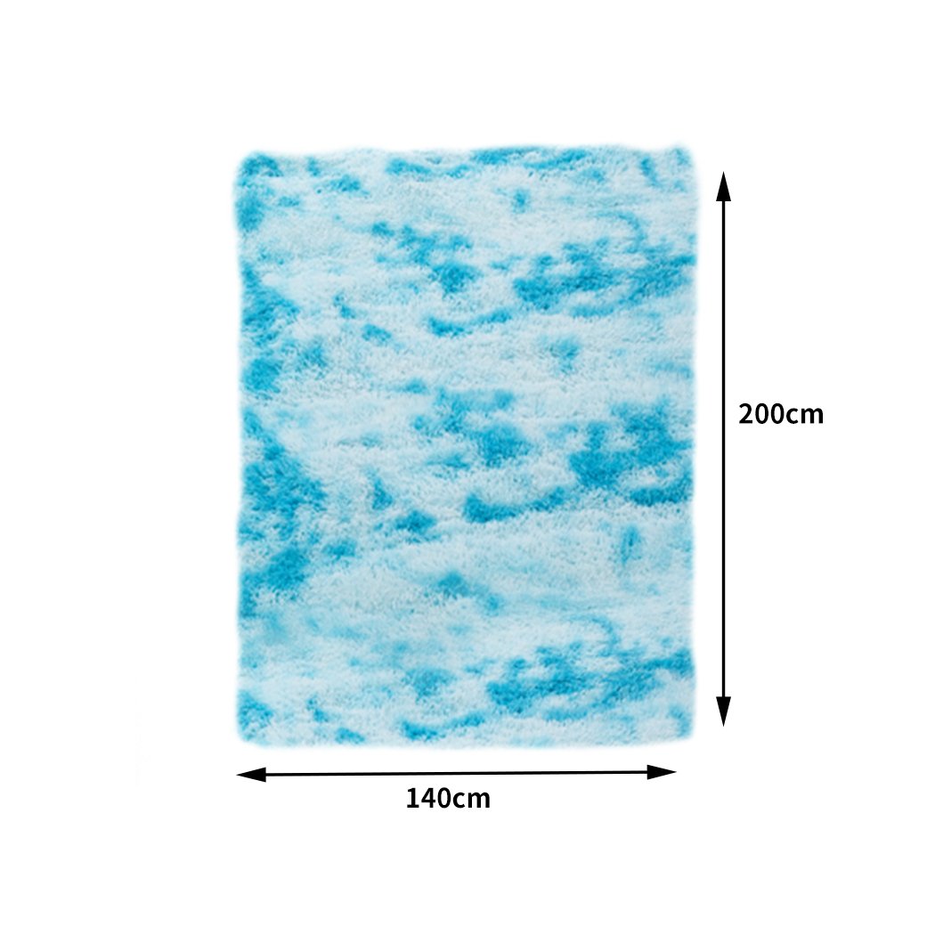 A large, soft shaggy floor rug with a vibrant tie-dyed pattern, showcasing its plush texture and anti-slip silicone bottom.