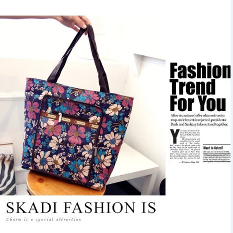 Foldable handbag featuring a vibrant flower pattern, made of durable nylon with gold hardware, perfect for women.