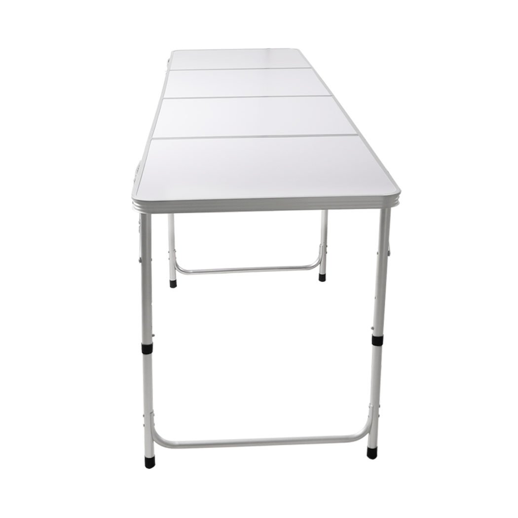 A lightweight and portable folding camping table set up outdoors, showcasing its sturdy aluminum frame and smooth MDF tabletop.