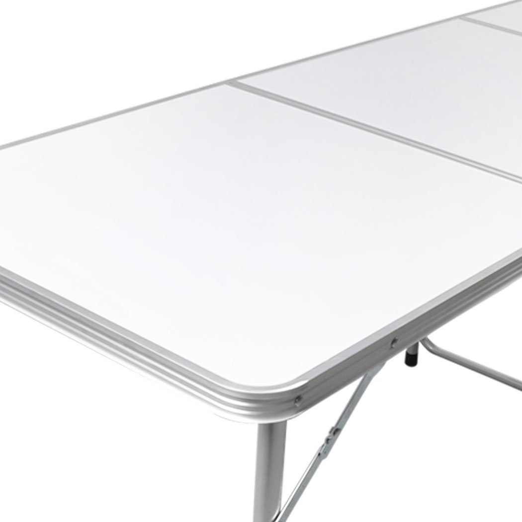 A lightweight and portable folding camping table set up outdoors, showcasing its sturdy aluminum frame and smooth MDF tabletop.