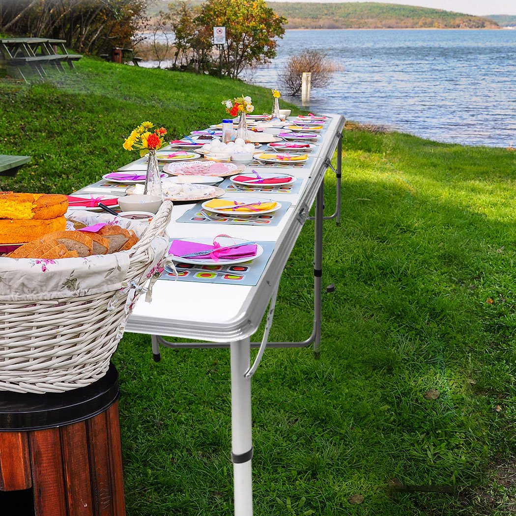 A lightweight and portable folding camping table set up outdoors, showcasing its sturdy aluminum frame and smooth MDF tabletop.