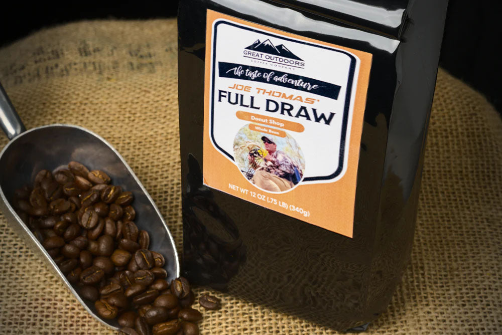 A steaming cup of Full Draw coffee surrounded by nature, symbolizing adventure and outdoor experiences.