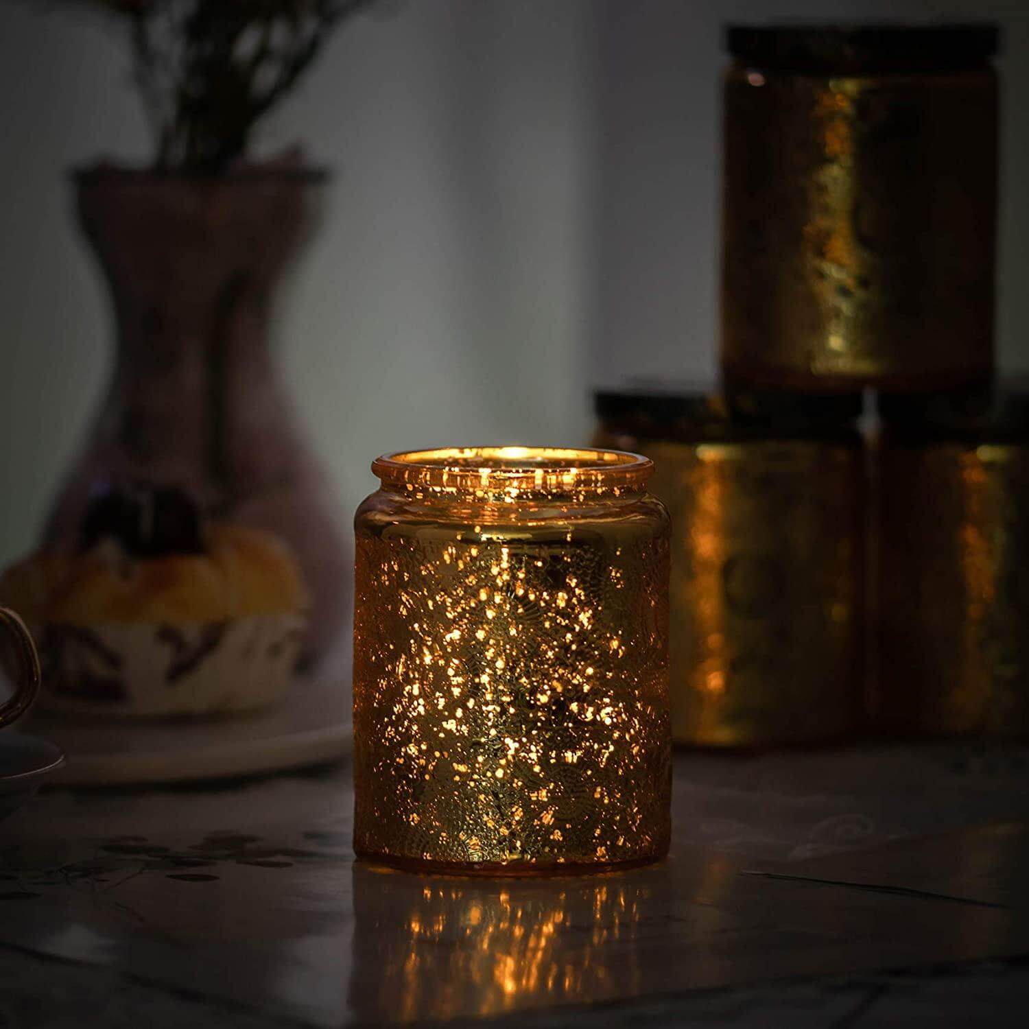 A luxurious gold 8oz glass jar candle, hand poured with soy and paraffin wax, glowing softly in a dark room.